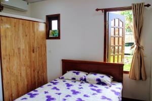 een slaapkamer met een bed met paarse en witte lakens en een raam bij CocoPalm Villa near Beach - Palm Room in Ấp Mỹ An