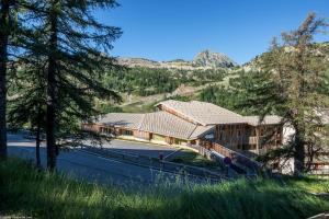 a resort building with trees and mountains in the background at Residence Les Terrasses d'Azur - maeva Home in Isola 2000
