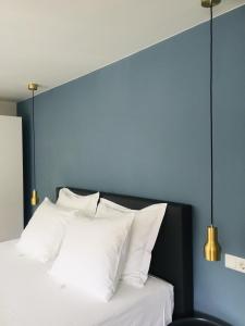 een bed met witte kussens en een blauwe muur bij Slapen op 11 in Bergen op Zoom