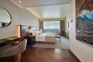 a hotel room with a bed and a large window at Les Suites at The Cliff Bay - PortoBay in Funchal