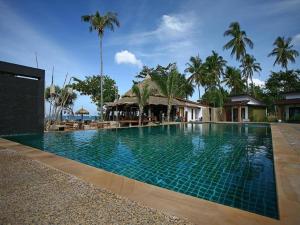 ein Swimmingpool vor einem Resort mit Palmen in der Unterkunft Coco Lanta Resort - SHA Extra Plus in Ko Lanta