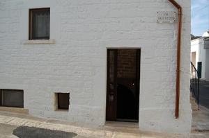 um edifício de tijolos brancos com uma porta preta em La Cantina em Alberobello