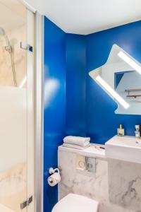 Baño azul con aseo y lavamanos en ibis budget Lyon Est Beynost en Beynost