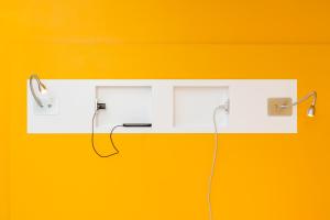 a pair of ear phones hanging on a yellow wall at ibis budget Lyon Est Beynost in Beynost