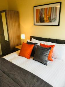 1 dormitorio con 1 cama con almohadas de color naranja y gris en AmberBlue@Epsom en Epsom