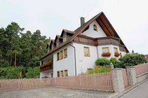 a large white house with a fence in front of it at Ferienwohnungen Lehner in Mitteleschenbach