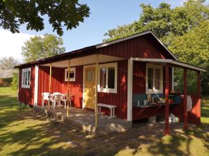 ein rotes winziges Haus mit einer Veranda und einem Tisch in der Unterkunft STF Hagaby/Lantgården Hostel in Löttorp