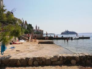 un grupo de personas en una playa con un crucero en Rab centar, en Rab