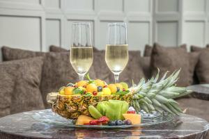 une corbeille de fruits et deux verres à vin sur une table dans l'établissement Hotel Martis Palace, à Rome