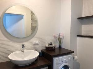 a bathroom with a sink and a mirror and a washing machine at Apartament w parku nad Zatoką in Puck
