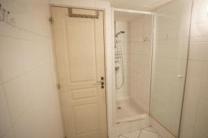 La salle de bains est pourvue d'une douche et d'une porte blanche. dans l'établissement Chez Jean Pierre - Room 1pers in a 17th century house - n 6, à Villar-dʼArêne