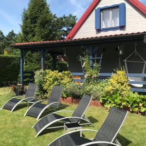 a group of chairs sitting in the grass in front of a house at Grey House in Dębki