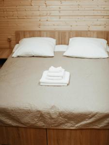a bed with two white towels on top of it at Touristic complex Taiezhnik in Manzherok