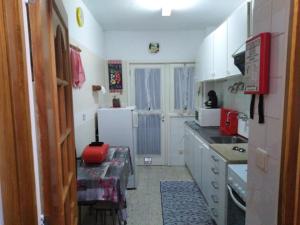 a kitchen with white cabinets and a red stool in it at Apartamento Do Silva in Mirandela