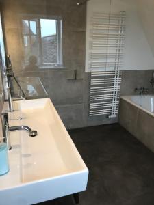 a bathroom with a white sink and a bath tub at Hûs lepen Wil in Hörnum +32 photos