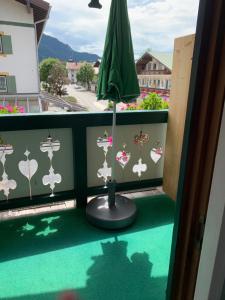 - un balcon avec un parasol vert et un sol vert dans l'établissement Ferienwohnung Giacomelli 3, à Rottach-Egern