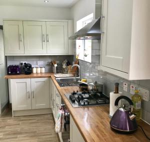 a kitchen with white cabinets and a stove top oven at The Woodfarm Lodge - 3 Bedroom House with free Parking in Oxford