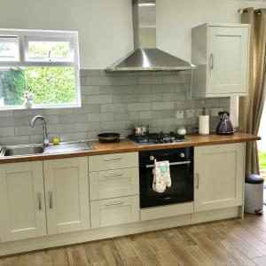 a kitchen with white cabinets and a stove top oven at The Woodfarm Lodge - 3 Bedroom House with free Parking in Oxford