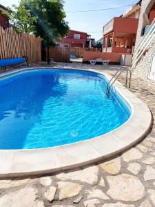 a swimming pool with blue water in a yard at Apartments Adriapag in Pag