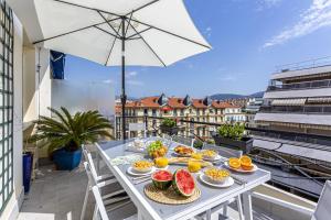 stół z jedzeniem na balkonie z parasolem w obiekcie MY CASA - Massenet w Nicei
