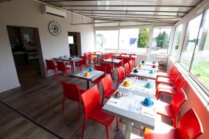 a dining room with tables and red chairs at Hotel Lune Etoile in Clermont-Ferrand