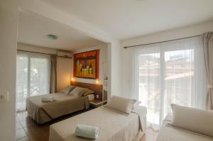 a bedroom with two beds and a large window at Pousada Borboleta in Morro de São Paulo