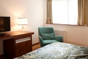 a bedroom with a bed and a chair and a desk at Garden Spa Boutique Hotel in Skopje