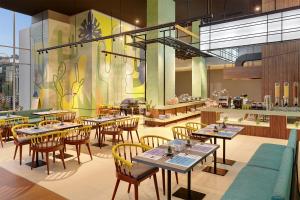 una sala da pranzo con tavoli e sedie e un ristorante di ibis Styles Jakarta Simatupang a Giacarta