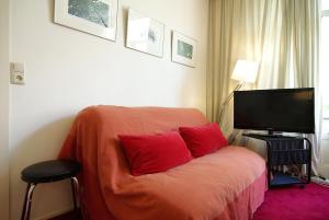a bedroom with a bed with red pillows and a television at Wooden Mill B&B in Amsterdam