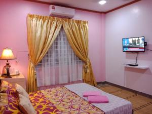 um quarto com uma cama com paredes cor-de-rosa e uma televisão em Jazepuri - Jaze 3 em Kuching