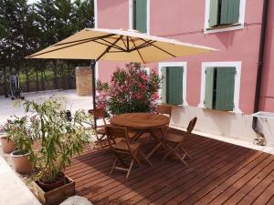 een houten tafel en stoelen onder een parasol op een terras bij La Bastide du Limon in Mormoiron