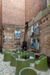 ein Zimmer mit grünen Stühlen und Tischen und einer Ziegelwand in der Unterkunft BANKS Antwerp in Antwerpen