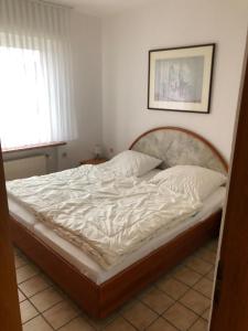 - une chambre avec un grand lit et des draps blancs dans l'établissement Haus Horst, à Schillig