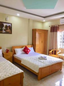 um quarto com 2 camas e almofadas vermelhas em Hải Lưu Hotel em Cái Rồng