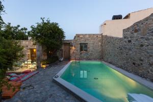 a swimming pool in front of a stone building at Muazzo Creta Stone House, a Fairytale Cottage, By ThinkVilla in Pigi