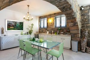 a kitchen with a glass table and green chairs at Muazzo Creta Stone House, Nature Escape with Pool, By ThinkVilla in Pigi