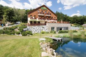 a building with a pond in front of it at Peras Wellness Hotel in Ludvíkov