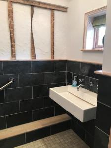 a bathroom with a white sink and black tiles at The White House in Takeley