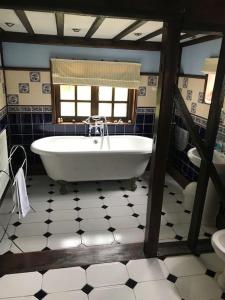 ein Bad mit einer Badewanne und einem Fenster in der Unterkunft The White House in Takeley