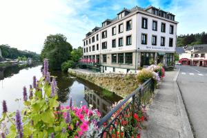 een gebouw naast een rivier met bloemen bij Hôtel Restaurant Du Château in Josselin