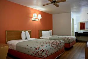 2 bedden in een hotelkamer met oranje muren bij Heritage Inn & Suites in El Dorado