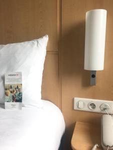 a hotel room with a bed with a pillow and a lamp at ibis Saint-Denis Stade Ouest in Saint-Denis
