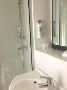 a bathroom with a sink and a shower with a mirror at ibis Saint-Denis Stade Ouest in Saint-Denis