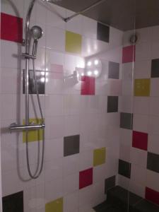 y baño con ducha y azulejos de colores. en Logis Hotel Les Gravades Ussel, en Ussel