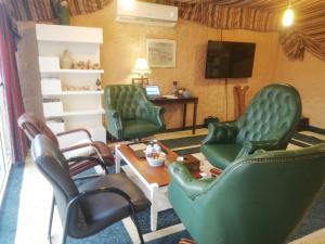 a waiting room with green chairs and a television at Beyout Guest Houses in Ma‘mad