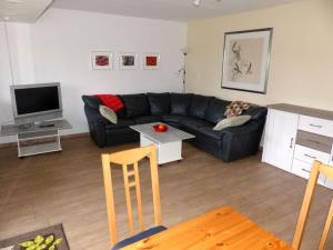 a living room with a black couch and a tv at Ferienwohnung Paula in Lichtenstein