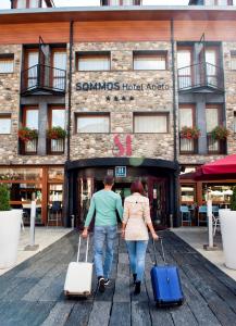 mężczyzna i kobieta idący ulicą z bagażem w obiekcie SOMMOS Hotel Aneto w mieście Benasque