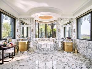 a bathroom with a tub and a table and windows at Le Meurice – Dorchester Collection in Paris