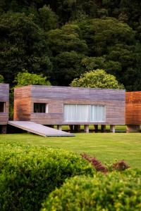 a house with a wooden facade in a field at Furnas Lake Forest Living in Furnas