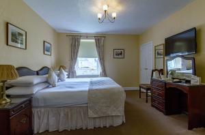Dormitorio con cama, escritorio y TV en Atholl Villa Guest House, en Pitlochry